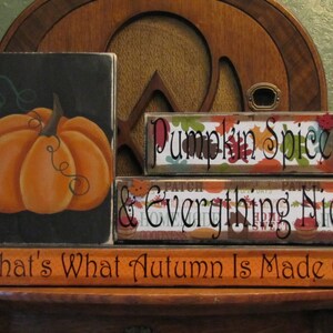 Puede incluir: Un conjunto de tres letreros de madera con texto de tem&aacute;tica oto&ntilde;al. El letrero superior dice "Pumpkin Spice", el letrero del medio dice "& Everything Nice", y el letrero inferior dice "That's What Autumn Is Made Of". El letrero superior tiene un patr&oacute;n de hojas de oto&ntilde;o y el letrero del medio tiene un patr&oacute;n de patchwork. El letrero inferior es naranja con texto negro.