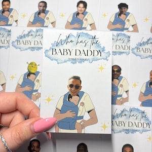 May include: Cards with illustrations of men holding babies in carriers. The text "Who has the BABY DADDY" is displayed on the cards. The cards have a scratch-to-reveal feature. The cards are white with blue and gold accents.