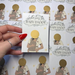 May include: A stack of "Who has the BABY DADDY" scratch-off cards. Each card features an illustration of a person holding a baby in a carrier. The text "Who has the BABY DADDY" is printed on the card.