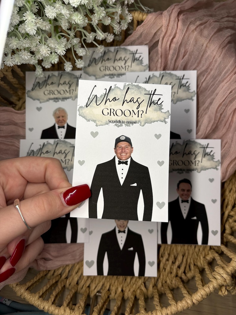 May include: A rectangular white card featuring the text Who has the GROOM? and Scratch to reveal. The card displays a graphic of a person wearing a black tuxedo with a white shirt and a black bow tie, surrounded by small grey heart icons.