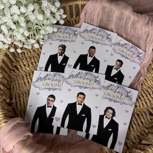 May include: A set of rectangular game cards featuring the text Who has the Groom? Scratch to reveal. Each card displays a different man in a black tuxedo and bow tie, accented with small light purple hearts and a watercolour-style purple header.