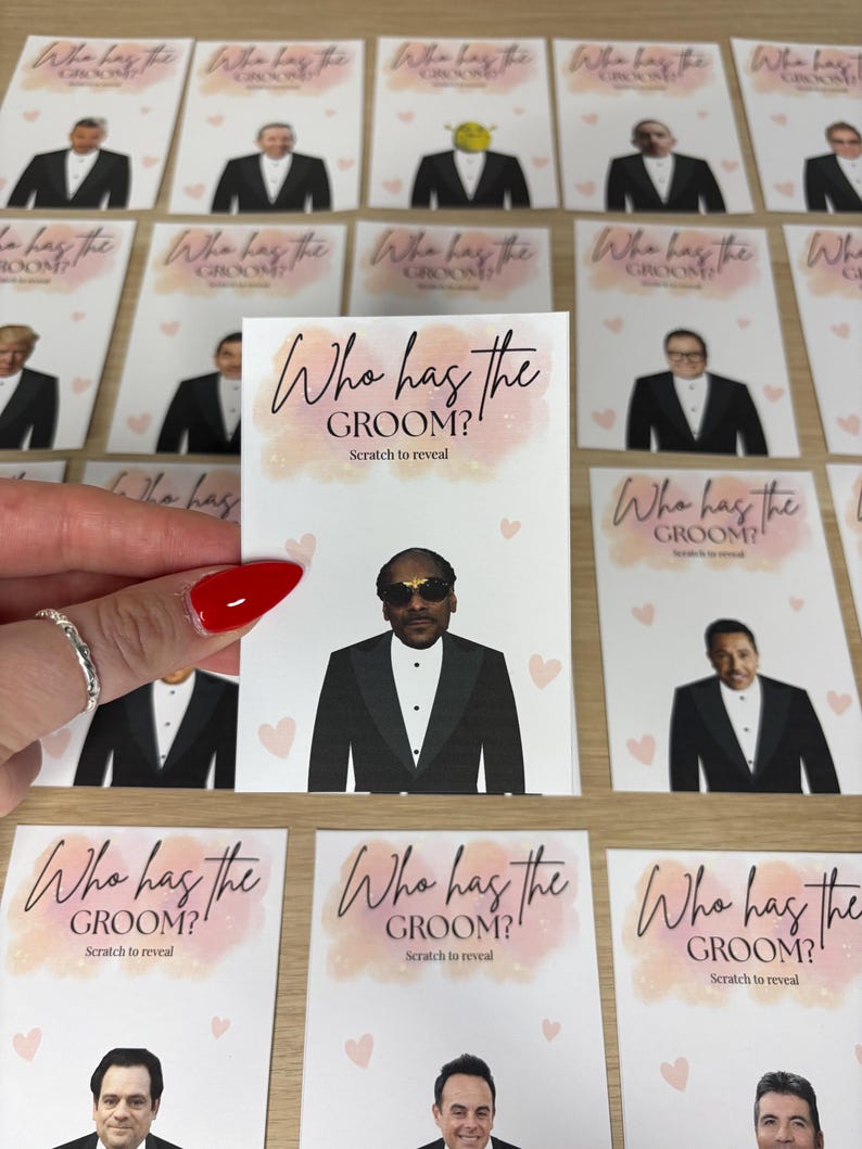 May include: A rectangular game card featuring the text Who has the GROOM? Scratch to reveal in black script and block lettering. The card displays a graphic of a person in a black tuxedo and sunglasses, surrounded by small light pink hearts.