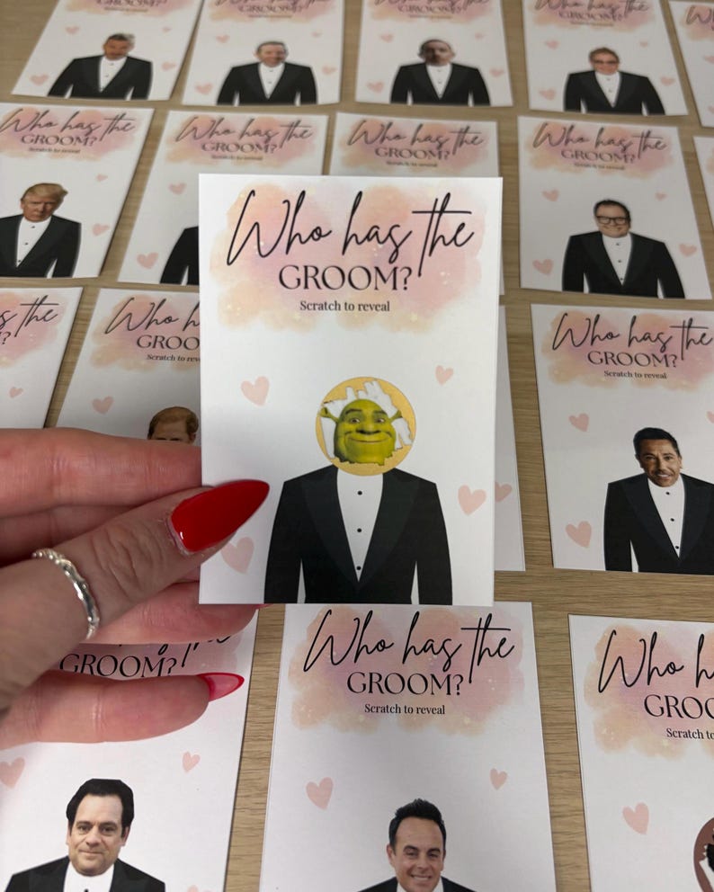 May include: A rectangular game card featuring the text Who has the GROOM? Scratch to reveal in black script and sans-serif font. The card displays a graphic of a tuxedo-clad figure with a circular scratch-off area revealing Shrek's face.