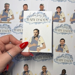 May include: A collection of "Who Has the Baby Daddy" scratch-off cards. Each card features a celebrity illustration holding a baby in a carrier. The cards have a blue watercolor design and the text "Who Has the Baby Daddy" with "Scratch to reveal".