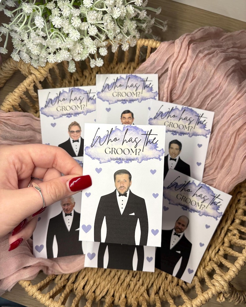 May include: A set of rectangular scratch-off game cards featuring the text Who has the GROOM? Scratch to reveal. Each card displays a different man in a black tuxedo and bowtie, accented with small light purple hearts and a watercolour-style purple header.