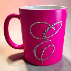 Könnte beinhalten: Ein Set aus drei Keramikbechern mit gesprenkelter, matter Oberfläche. Die Becher sind in Creme-, Hellgrau- und Dunkelgrautönen gehalten. Jeder Becher hat ein schlichtes, minimalistisches Design.