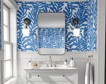 May include: A bathroom vanity featuring a white cabinet with a marble countertop, a rectangular mirror, and two wall-mounted light fixtures. The walls are covered in wallpaper with a bold blue and white organic leaf or coral pattern.