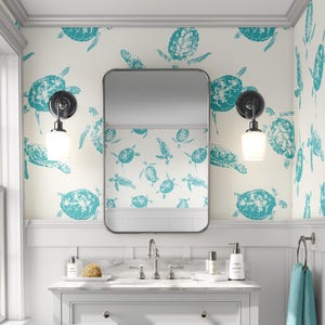 May include: A white bathroom with teal sea turtle wallpaper. The bathroom has a white vanity with a silver faucet and a mirror above the sink. There are two silver sconces with white glass shades on the wall.