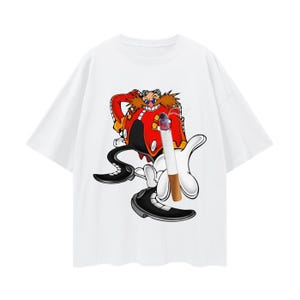 May include: White t-shirt with a cartoon image of Dr. Eggman from the Sonic the Hedgehog video game series. He is wearing a red and black outfit and holding a cigarette.
