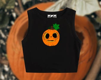 May include: Black crop top featuring a cartoon pumpkin face graphic. The pumpkin is orange with a green leaf and stem. The top has the letters "M&M" in white at the top. Perfect for Halloween.