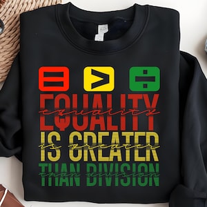 May include: Black sweatshirt with a graphic design featuring the words "Equality is greater than division" in red, yellow, and green. The graphic also includes an equals sign, a greater than sign, and a division sign.