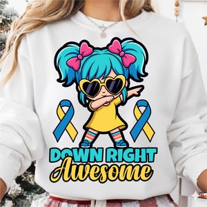 Op de afbeelding: Witte sweatshirt met een cartoonmeisje met blauw haar, roze strikken en hartvormige zonnebril. Het meisje doet een dab, met blauwe en gele linten en de tekst "DOWN RIGHT Awesome".