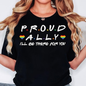 Könnte beinhalten: Schwarzes T-Shirt mit dem Text "P.R.O.U.D. A.L.L.Y." in Weiß mit Regenbogenherzen auf beiden Seiten des Textes. Der Text "I'll be there for you" befindet sich unter dem Haupttext.