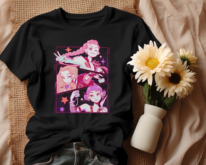 May include: Black t-shirt featuring a colorful anime-style graphic of three female characters. Each character is framed in a pink and purple rectangle with stars. The shirt is made of a soft material and is suitable for casual wear.