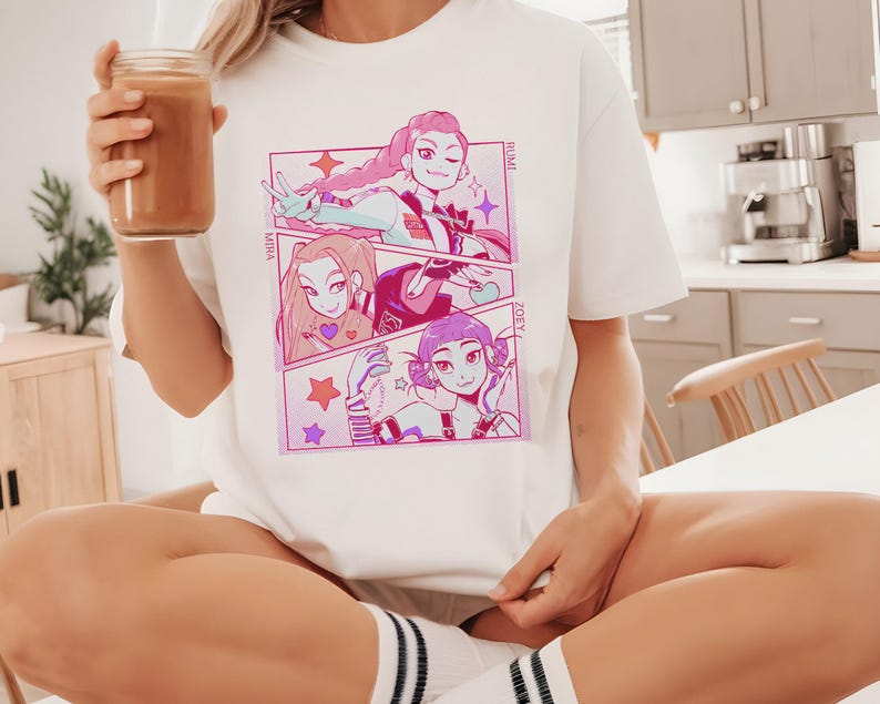 May include: White t-shirt featuring a colorful anime-style graphic. The graphic is divided into three panels, each showcasing a different character with pink and purple accents. The names "MIHA", "RUMI", and "ZOEY" are printed on the shirt.