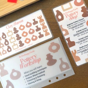 May include: Three clear plastic cards with pottery-themed designs and text. One card reads "Clay Haven" and features pottery illustrations. Another card says "Pottery Workshop" and lists techniques. The third card says "Pottery Shop" and lists class options.