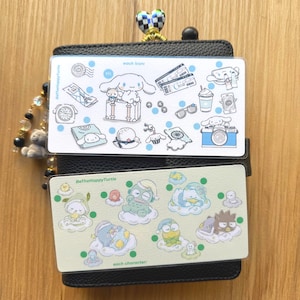 May include: Black card holder with two decorative inserts. The top insert features blue icons and the text "each icon". The bottom insert has cartoon characters and the text "each character". A beaded charm hangs from the top.