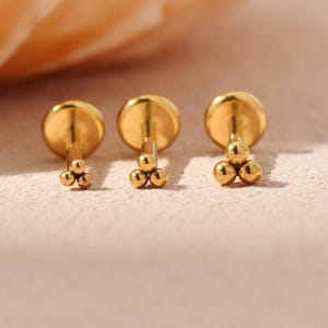 May include: A white ceramic mug with a black handle and the text "But First, Coffee" in a black, handwritten-style font. The mug is on a white surface.