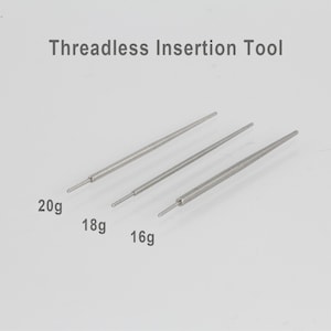 May include: Three silver threadless insertion tools, labelled 20g, 18g, and 16g. The tools are slender and tapered, designed for inserting threadless body jewellery. The text "Threadless Insertion Tool" is above the tools.