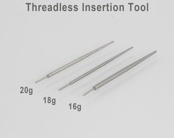 May include: Three silver threadless insertion tools of varying sizes, labeled 20g, 18g, and 16g. The tools are slender and tapered, designed for inserting threadless body jewelry. The text "Threadless Insertion Tool" is above the tools.