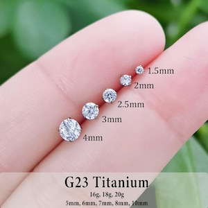 May include: Five round, clear, prong-set stud earrings made of G23 titanium, arranged by size from 1.5mm to 4mm. The text G23 Titanium, 16g, 18g, 20g, and 5mm, 6mm, 7mm, 8mm, 10mm is printed at the bottom of the image for reference.