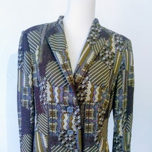 May include: A brown, green, and purple patterned blazer with a button closure. The blazer has a geometric design and is made of a textured fabric.