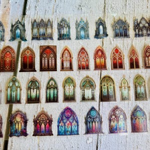 May include: A collection of individual stickers featuring various gothic arch window designs. The stickers display intricate architectural details, stained glass patterns, and diverse color palettes including deep reds, blues, greens, and warm golden tones.