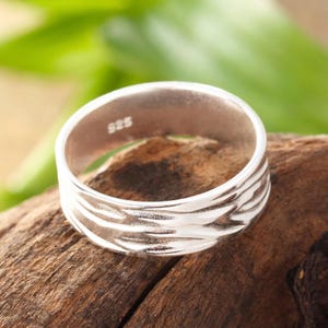 May include: A silver ring with a textured, wavy design. The ring is marked with "925" on the inside.