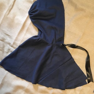 May include: A navy blue hooded cape with a black ribbon tie.