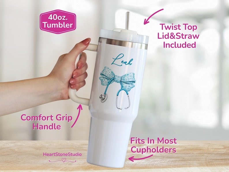 May include: White 40 oz. tumbler with a teal bow and stethoscope design. The tumbler has a comfort grip handle and includes a twist-top lid and straw. The tumbler is designed to fit in most cupholders. The name "Leah" is written on the tumbler.