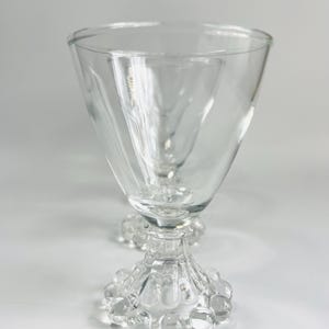 May include: Set of two clear glass wine glasses with a beaded base.
