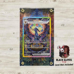 May include: A Pokémon Umbreon EX card, featuring a dark blue creature with a colorful background. The card is encased in a protective sleeve with decorative accents. The text "Moon Mirage" and "Onyx" are visible.