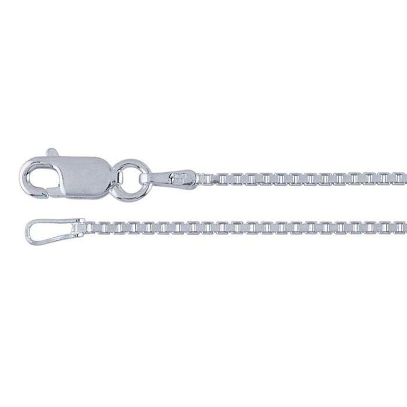 May include: A silver-colored box chain necklace with a lobster clasp closure. The chain is composed of small, square links, and the clasp is attached to a circular ring. The necklace is displayed against a white background.