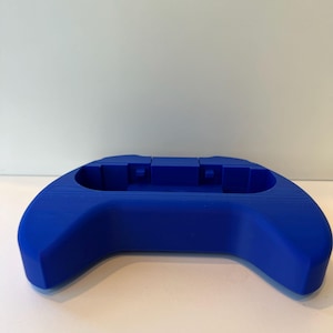 May include: A blue silicone controller stand for a video game console.