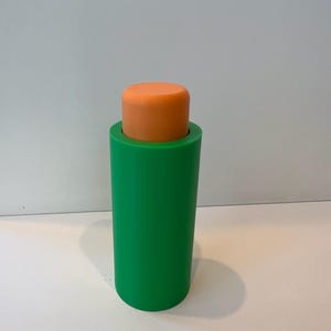 Pu&ograve; includere: Un tappo per bottiglia cilindrico verde e arancione. La parte superiore del tappo &egrave; arancione e la parte inferiore &egrave; verde.