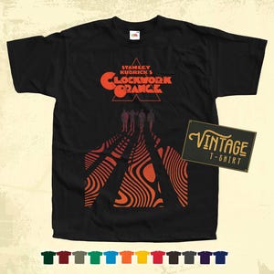 May include: Black t-shirt with a vintage design featuring the title "Stanley Kubrick's Clockwork Orange" in red and orange text. The design also includes a stylized image of four figures walking in a line.