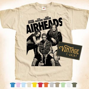 May include: A vintage beige t-shirt with a black print of the movie "Airheads" featuring Brendan Fraser, Steve Buscemi, and Adam Sandler. The text "Airheads" is in large, bold letters.