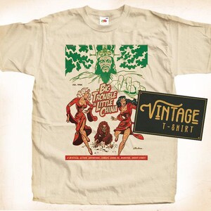 May include: A vintage t-shirt featuring a comic book illustration of a man with a crown and a woman in a red dress. The text on the shirt reads "Big Trouble in Little China".