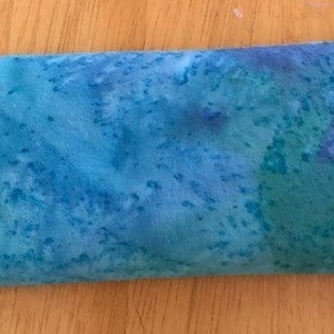 May include: A blue and green tie-dye fabric eye pillow. The pillow is rectangular and has a soft, textured surface.