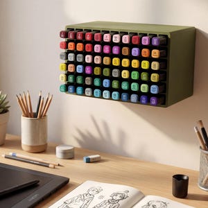 Peut inclure: Un bureau en bois avec du matériel d'art. Une tablette de dessin noire avec un stylet, un carnet de croquis avec des dessins, des crayons et un organiseur de marqueurs mural rempli de marqueurs colorés. Une petite plante succulente en pot est également sur le bureau.