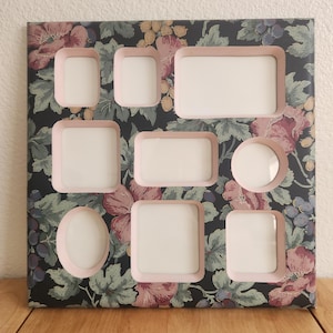 Peut inclure: Un cadre photo collage à ouvertures multiples avec un fond sombre orné d'un motif floral de fleurs roses, de feuilles vertes et de raisins bleus. Le cadre présente huit ouvertures de formes et tailles variées, bordées d'un liseré rose clair.