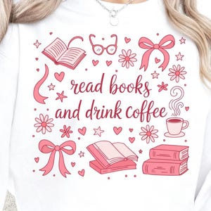 以下が含まれることがあります： 「read books and drink coffee」と書かれたピンク色のグラフィックが特徴の白いスウェットシャツ。デザインには、本、メガネ、花、リボン、ハート、星が含まれています。湯気の立つコーヒーカップも描かれています。