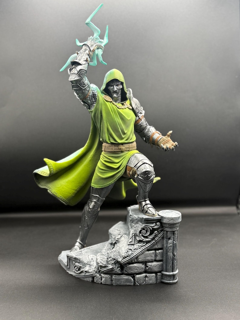 May include: A detailed figurine of a character wearing silver metallic armor and a green hooded tunic. The figure stands on a stone-textured base, holding a translucent light blue lightning bolt effect in one raised hand and reaching out.
