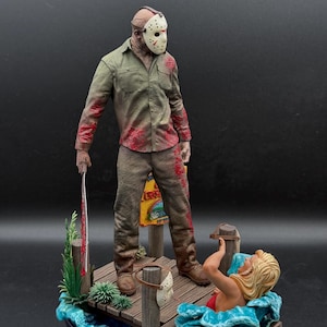 May include: A detailed figurine set featuring a character wearing a white hockey mask and a blood-stained olive green shirt and brown pants, holding a machete on a wooden dock. A blonde figure is in the blue water, with a Friday the 13th sign.