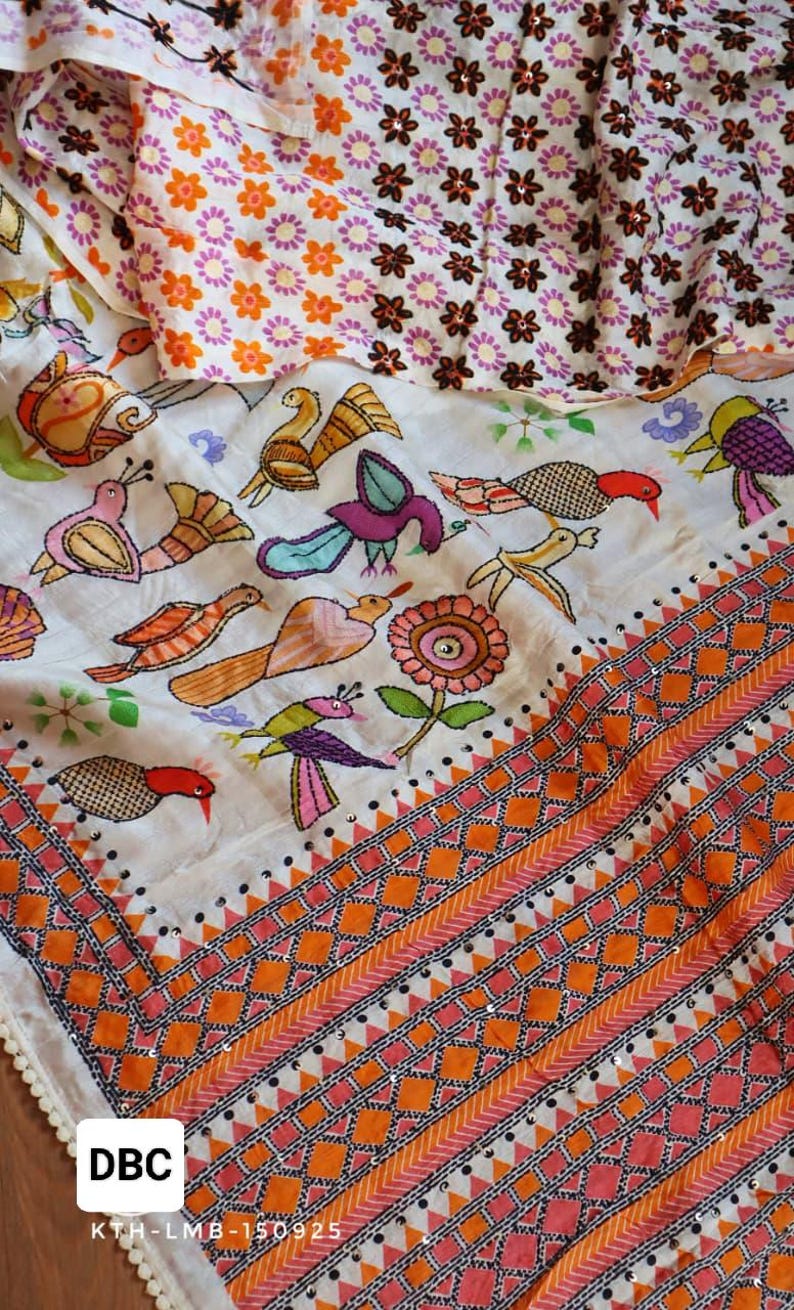 May include: A white textile with colorful embroidered birds and floral patterns. The design includes orange, pink, and purple accents, with a geometric border and the text "DBC".