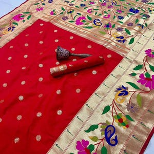 May include: A vibrant red sari with gold floral embroidery and a decorative border. The sari features a repeating pattern of small gold flowers and the word "Red" in the top left corner.