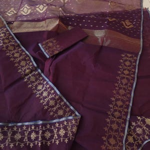 May include: A deep purple fabric set with gold embroidered floral patterns. The set includes a solid-colored fabric and a sheer fabric with gold geometric designs. The edges are trimmed with gold and blue accents. The fabric is likely used for clothing or home decor.