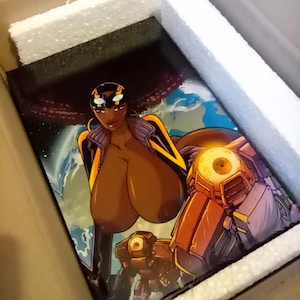 Puede incluir: Impresión de cómic que representa a una mujer de piel oscura en un entorno futurista, con un fondo espacial y figuras robóticas. La impresión está empaquetada en una caja de cartón con espuma protectora.