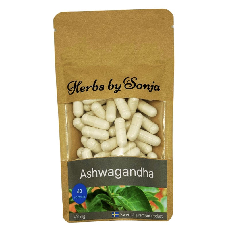 Może przedstawiać: Brązowa papierowa torebka z przezroczystym okienkiem, w kt&oacute;rym widać białe kapsułki. Torebka ma nadrukowany tekst "Herbs by Sonja" i "Ashwagandha". Torebka ma r&oacute;wnież etykietę z tekstem "60 kapsułek" i "400 mg".
