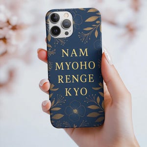 Puede incluir: Funda de teléfono azul marino con detalles florales dorados y el texto "NAM MYOHO RENGE KYO" en dorado. La funda tiene un acabado mate y está diseñada para un smartphone.